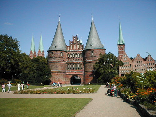 WG Zimmer Lübeck - Wahrzeichen Lübecks: das Holstentor; links die Türme der Marienkirche, rechts der Turm der Petrikirche, davor die historischen Salzspeicher. Aufnahme 2004..